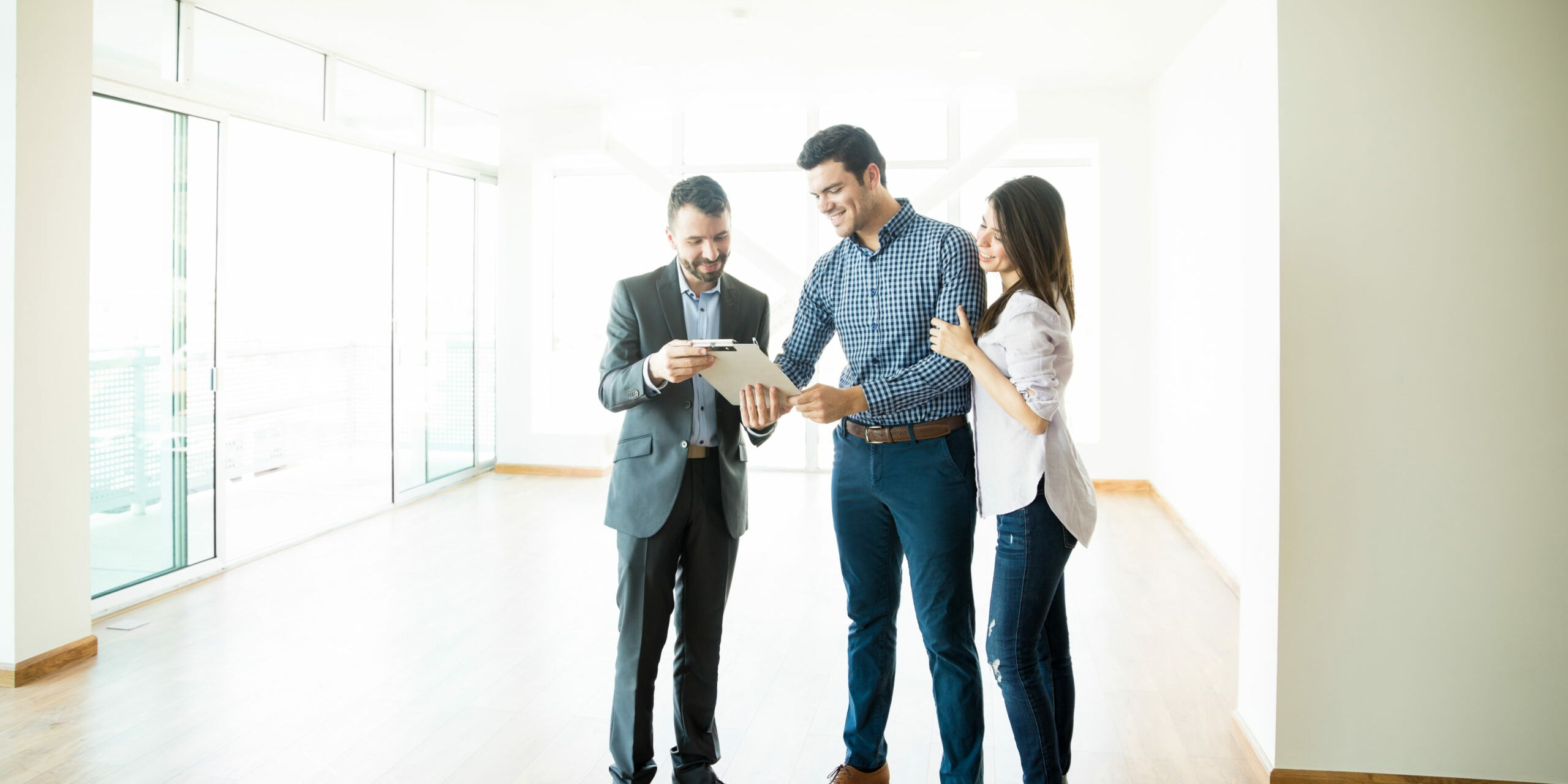 Couple Signing Sale Purchase Agreement By Broker In New Home