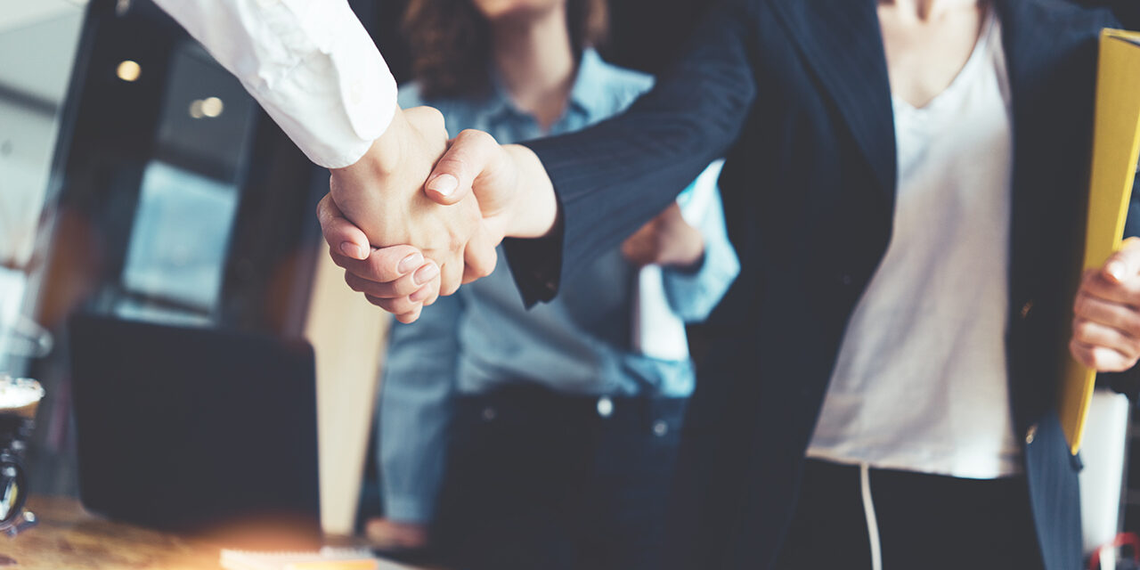 Young business people shaking hands in the office. Finishing suc