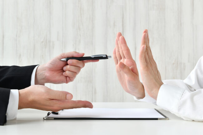契約を迫るビジネスマンとそれを拒む人物の手元 Refus de vente
