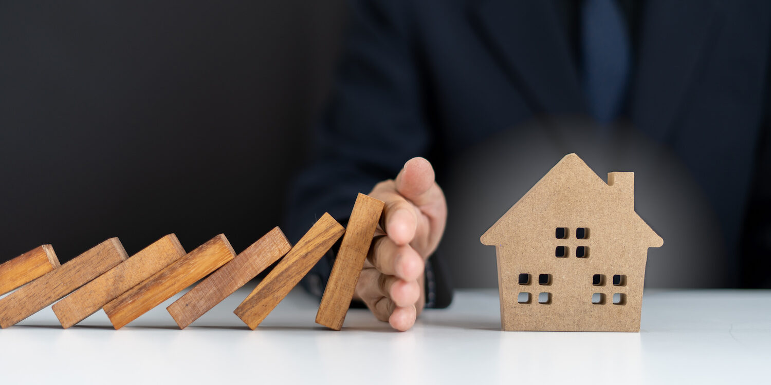 Insurance agents or family leaders are using hands to prevent Dominos from falling into the house. Prevention of external hazards. Home insurance plan Agent immobilier bon de visite