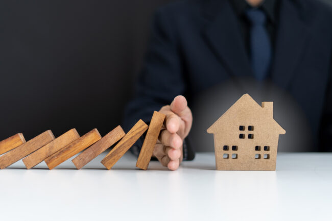 Insurance agents or family leaders are using hands to prevent Dominos from falling into the house. Prevention of external hazards. Home insurance plan Agent immobilier bon de visite