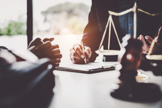Business woman and lawyers discussing contract papers with brass scale on wooden desk in office. Law, legal services, advice, Justice concept.