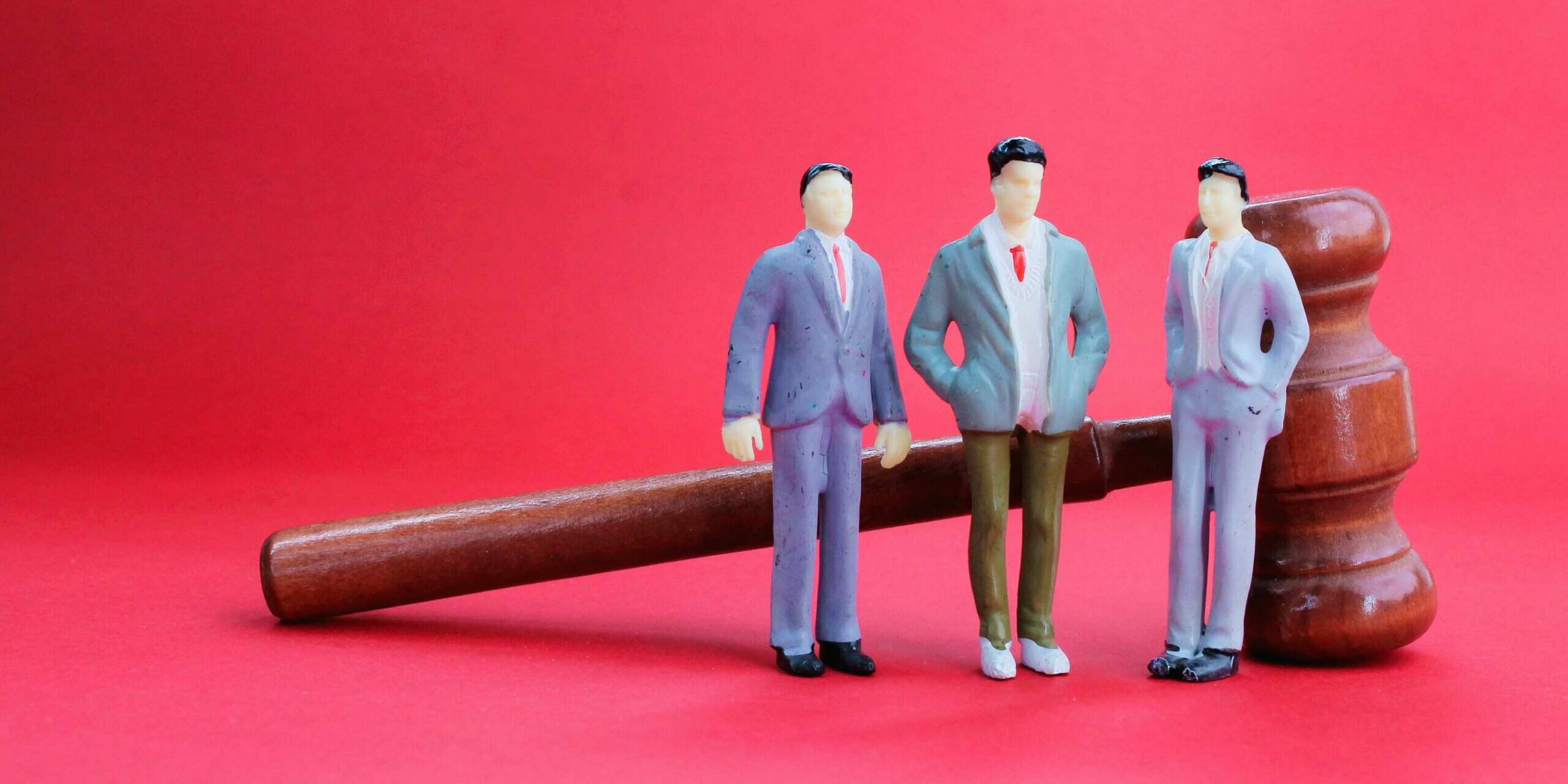 three miniature people with a judge’s gavel behind. employment l délégation créances loi